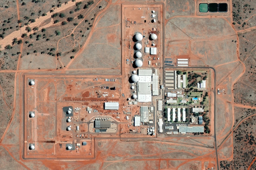 A satellite image shows a number of buildings and domes on a site surrounded by red dirt.