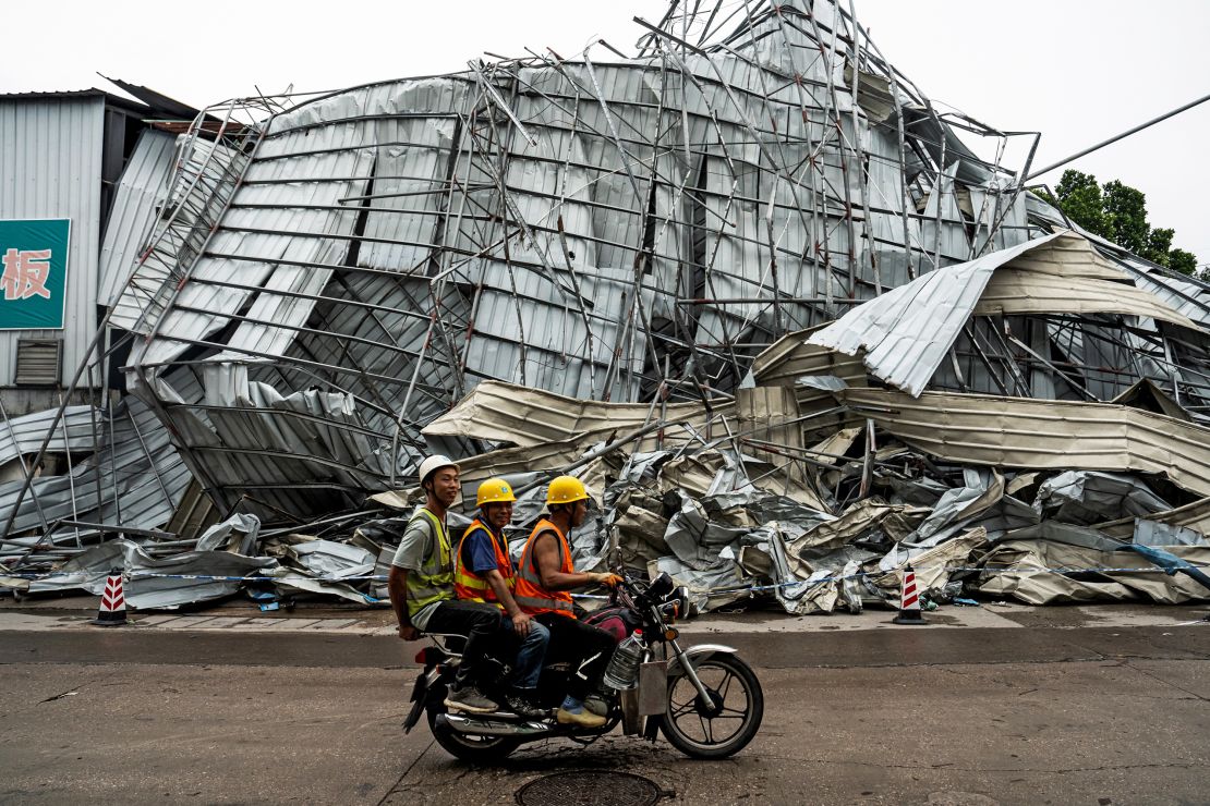 People drive past a damaged building on Sunday after the tornado hit southern China's Guangdong province.