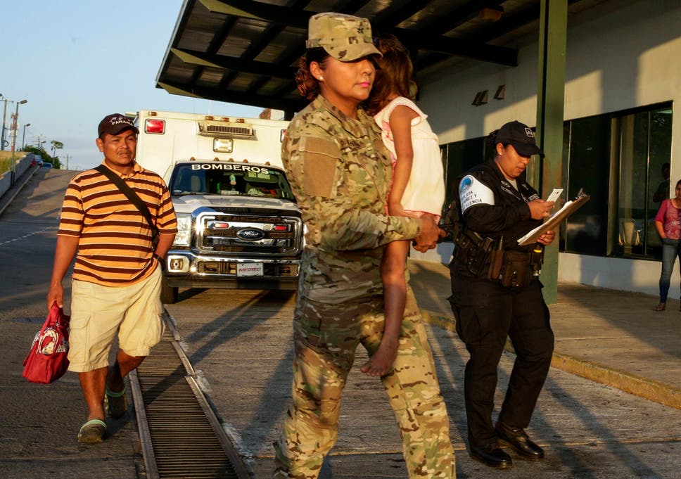 Jose Gonzalez, left, follows his 5-year-old daughter, carried by a police officer, as they leave a hospital in Santiago, Panama. Gonzalez's wife and five of their children are among seven people killed in a religious ritual in the Ngabe Bugle indigenous community