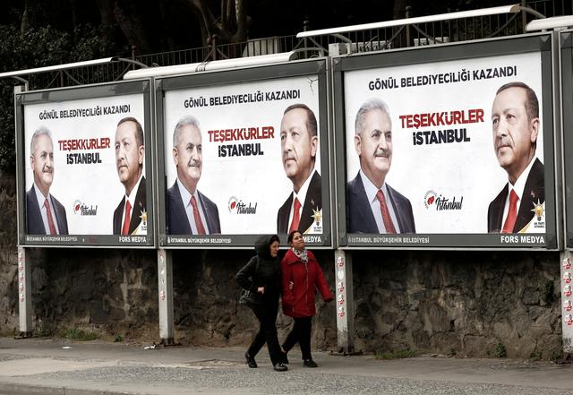 FILE PHOTO: People walk past by AK Party billboards with pictures of Turkish President Tayyip Erdogan and mayoral candidate Binali Yildirim in Istanbul, Turkey, April 1, 2019. REUTERS/Murad Sezer/File Photo