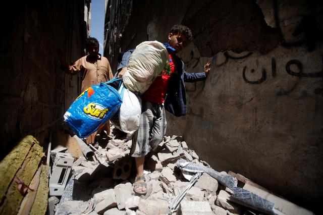 People carry their belongings at the site of an air strike launched by the Saudi-led coalition in Sanaa, Yemen  May 16, 2019. REUTERS/Mohamed al-Sayaghi