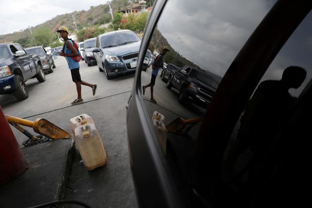 FILE PHOTO: A man walks past fuel containers while vehicle queue to refuel with gasoline in Puerto Cabello, Venezuela May 17, 2019. REUTERS/Manaure Quintero/File Photo