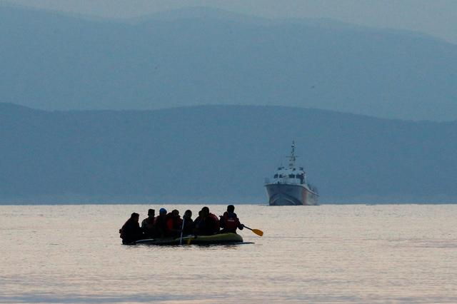 FILE PHOTO: Migrants in a dinghy paddle their way on the Mediterranean Sea to attempt crossing to the Greek island of Kos, as a Turkish Coast Guard ship patrols off the shores off Bodrum, Turkey, September 19, 2015.  REUTERS/Umit Bektas/File Photo