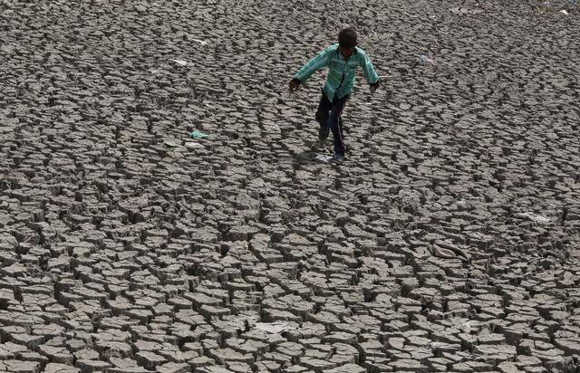 FILE PHOTO: A boy walks through a dried lakebed in Ahmedabad, India, May 1, 2019. REUTERS/Amit Dave
