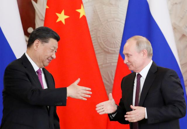 Russian President Vladimir Putin attempts to shake hands with his Chinese counterpart Xi Jinping during a meeting in Moscow, Russia, June 5, 2019. REUTERS/Evgenia Novozhenina