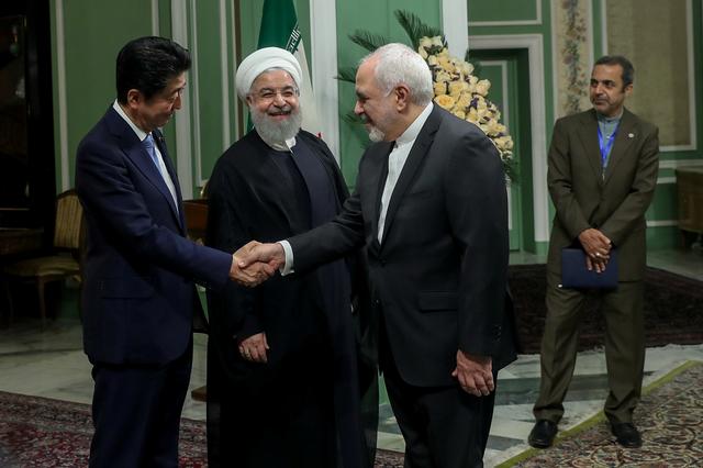 Iranian Foreign Minister Mohammad Javad Zarif shakes hands with Japan's Prime Minister Shinzo Abe, as Iranian President Hassan Rouhani looks on in Tehran, Iran, June 12, 2019. Official Iranian President website/Handout via REUTERS