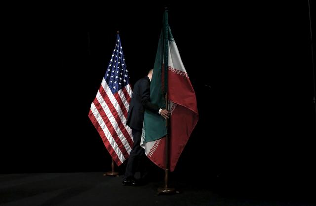 A staff member removes the Iranian flag from the stage after a group picture with foreign ministers and representatives of the U.S., Iran, China, Russia, Britain, Germany, France and the European Union during the Iran nuclear talks at the Vienna International Center in Vienna, Austria July 14, 2015.   REUTERS/Carlos Barria/File Photo