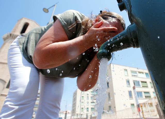 A woman cools off in a water fountain in Marseille as a heatwave hits much of the country, France, June 28, 2019.  REUTERS/Jean-Paul Pelissier