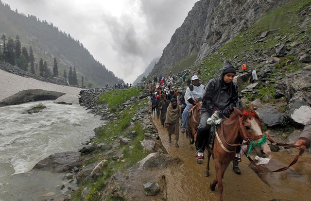 FILE PHOTO: Hindu pilgrims travel, either on ponies or on foot, along a track besides a glacier-fed stream during their annual pilgrimage to holy cave of Lord Shiva, in Pishutop, 114 km (71 miles) southeast of Srinagar June 25, 2012. REUTERS/Fayaz Kabli/File Photo