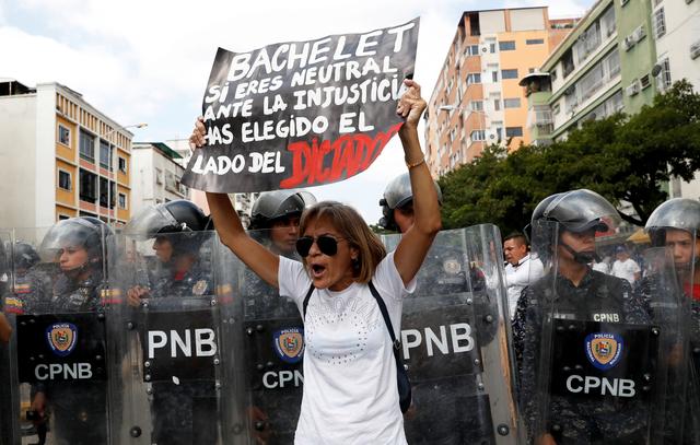 FILE PHOTO: Opposition supporters take part in a rally against Venezuelan President Nicolas Maduro's government in Caracas, Venezuela March 9, 2019. Placard reads Bachelet, if you are neutral towards the injustice, you have chosen the side of the dictatorship. REUTERS/Carlos Garcia Rawlins/File Photo