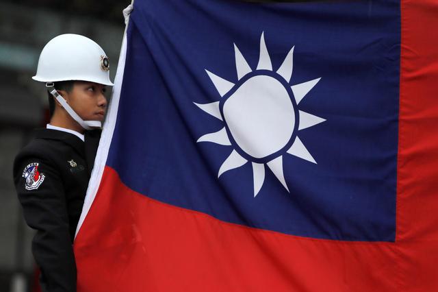 FILE PHOTO: A military honour guard holds a Taiwanese national flag as he attending flag-raising ceremony at Chiang Kai-shek Memorial Hall, in Taipei, Taiwan March 16, 2018. REUTERS/Tyrone Siu/File Photo