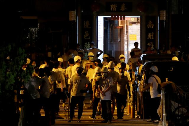 Men in white T-shirts and carrying poles are seen in Yuen Long after attacking anti-extradition bill demonstrators at a train station in Hong Kong, China, July 22, 2019. REUTERS/Tyrone Siu    