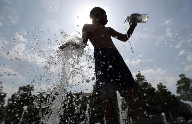 A boy plays with water in a fountain on a hot summer day in Brussels, Belgium, July 25, 2019. REUTERS/Yves Herman