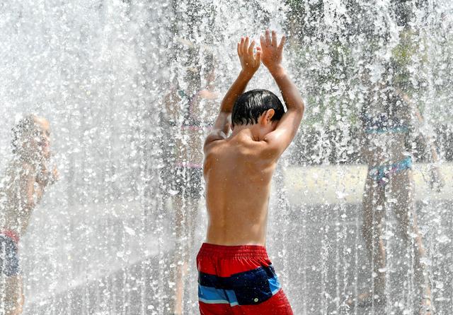 People cool off during a sunny day at the Rijksmuseum fountain in Amsterdam, July 25, 2019. REUTERS/Piroschka van de Wouw