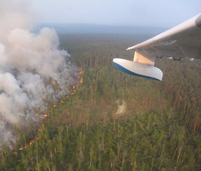 An aerial view through an aircraft window shows flame and smoke rising from a wildfire in Krasnoyarsk region, Russia in this handout picture obtained by Reuters on August 1, 2019. Russian Emergencies Ministry in Krasnoyarsk region/Handout via REUTERS