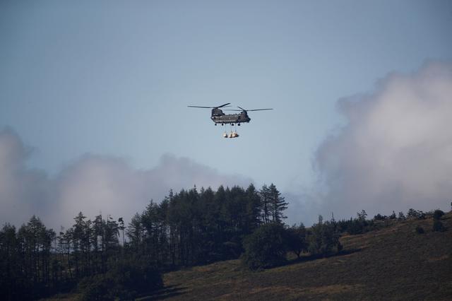 A Chinook helicopter carries sand bags to the top of the dam after a nearby reservoir was damaged by flooding, in Whaley Bridge, Britain August 2, 2019. REUTERS/Phil Noble