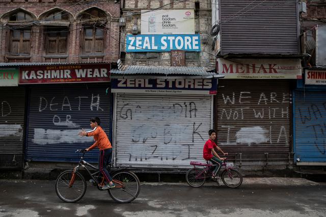 Kashmiri boys cycle in an empty street during restrictions after the scrapping of the special constitutional status for Kashmir by the government, in Srinagar, August 14, 2019. REUTERS/Danish Siddiqui