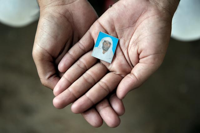 FILE PHOTO: Irshad Khan, 24, holds a picture of his late father Pehlu, 55, in Jaisinghpur, India, June 2, 2017. REUTERS/Cathal McNaughton/File Photo