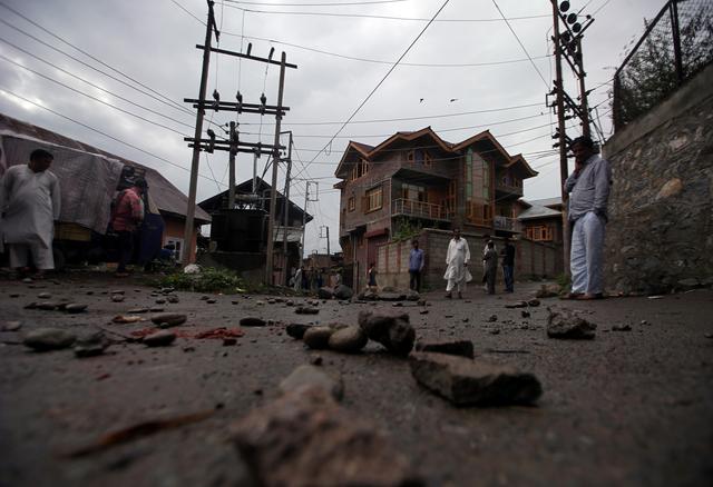 People walk on a road covered with stones and pieces of bricks during restrictions after the government scrapped the special constitutional status for Kashmir, in Srinagar August 14, 2019. REUTERS/Danish Ismail