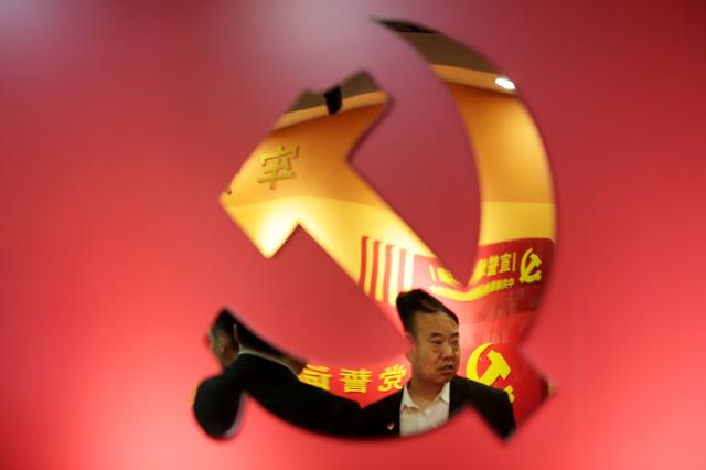 FILE PHOTO: Party members are reflected on a party emblem of the Communist Party of China (CPC) as they gather to attend a weekly group study at Tidal Star Group's party activity room in Beijing, China, February 25, 2019. REUTERS/Jason Lee