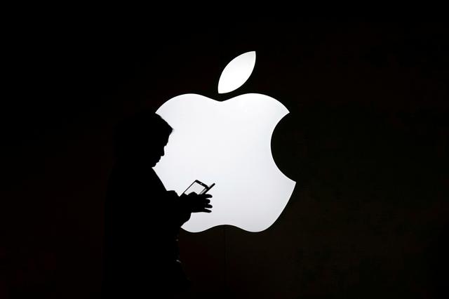 FILE PHOTO: A woman looks at the screen of her mobile phone in front of an Apple logo outside its store in Shanghai, China July 30, 2017. REUTERS/Aly Song/File Photo