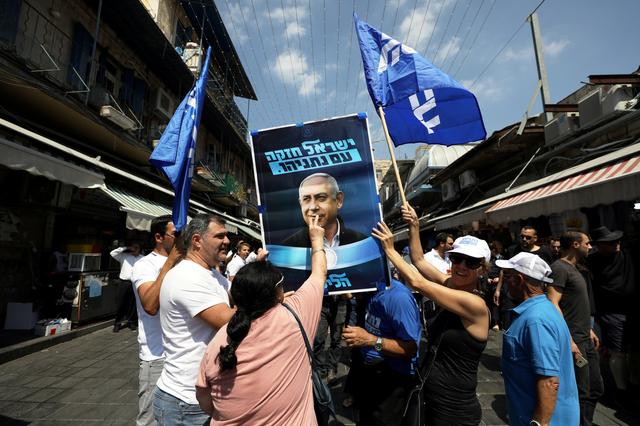 FILE PHOTO: A supporter of the Israeli Likud party kisses an election campaign poster depicting Israel iPrime minister Benjamin Netanyahu at the market in Jerusalem September 13, 2019 REUTERS/ Ammar Awad/File Photo