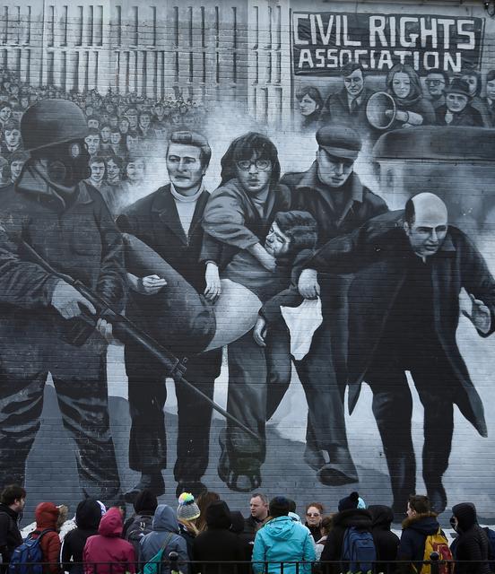 FILE PHOTO: Tourists stand in front of a mural depicting the Bloody Sunday events, in Londonderry, Northern Ireland March 14, 2019. REUTERS/Clodagh Kilcoyne/File Photo