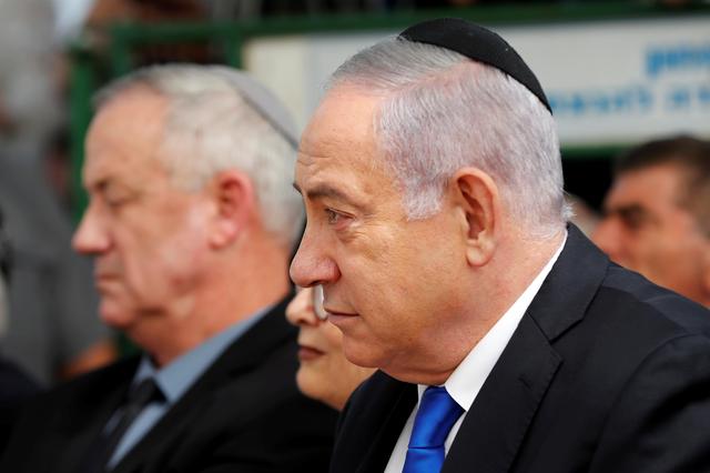 FILE PHOTO: Israeli Prime Minister Benjamin Netanyahu looks on as he sits next to Benny Gantz, leader of the Blue and White party, during a memorial ceremony for late Israeli President Shimon Peres, at Mount Herzl in Jerusalem September 19, 2019. REUTERS/Ronen Zvulun/File Photo