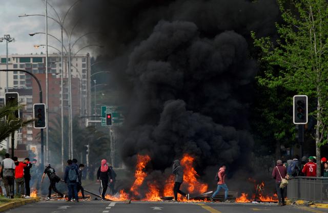 Demonstrators stand next to a burning barricade as increase in public transport prompted Chile's President Sebastian Pinera to declare a state of emergency, in Concepcion, Chile October 20, 2019.  REUTERS/Jose Luis Saavedra