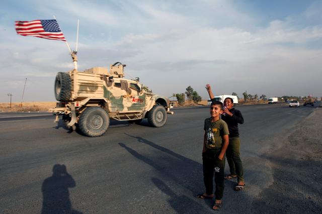 Boys wave towards a convoy of U.S. vehicles withdrawing from northern Syria, in Erbil, Iraq October 21, 2019. REUTERS/Azad Lashkari
