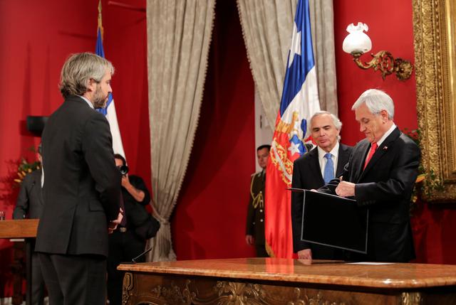Chile's newly appointed Interior Minister Gonzalo Blumel looks on as Chilean President Sebastian Pinera signs a document next to former minister Andres Chadwick during a cabinet reshuffle at the government house in Santiago, Chile October 28, 2019. REUTERS/Ivan Alvarado