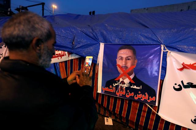 An Iraqi demonstrator takes a photo of a poster of Asaad al-Edani, Basra governor and a candidate for the prime minister office during ongoing anti-government protests in Baghdad, Iraq December 26, 2019. REUTERS/Khalid al-Mousily