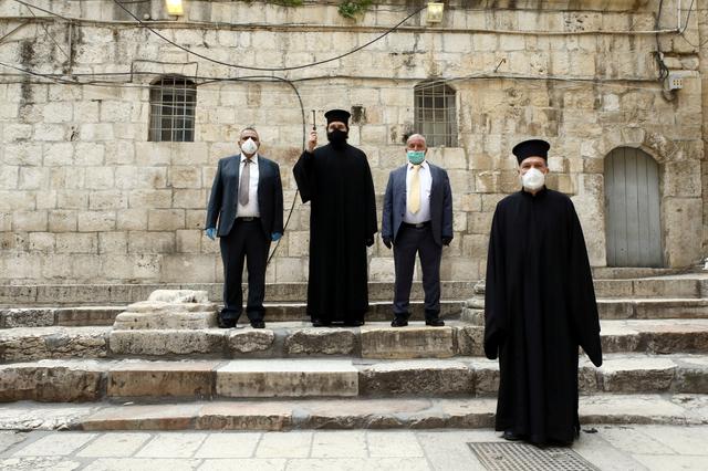 Orthodox Christian clergymen and church officials wearing face masks stand outside the Church of the Holy Sepulchre in Jerusalem on the day that Greek Orthodox church authorities celebrate Good Friday in Jerusalem's Old City April 17, 2020. REUTERS/ Ammar Awad