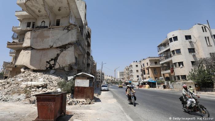 Motorbikes riding past ruined building in Idlib. (Getty Images/O. Haj Kadour)