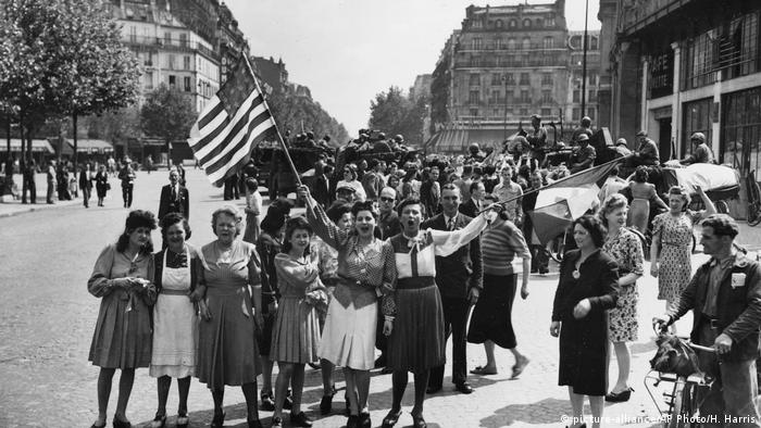 French civilians with hastily made American and French flags greet U.S. and Free French troops entering Paris, France, on August 25, 1944